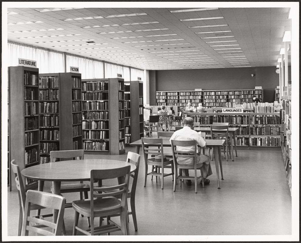 man reading at table in library stacks