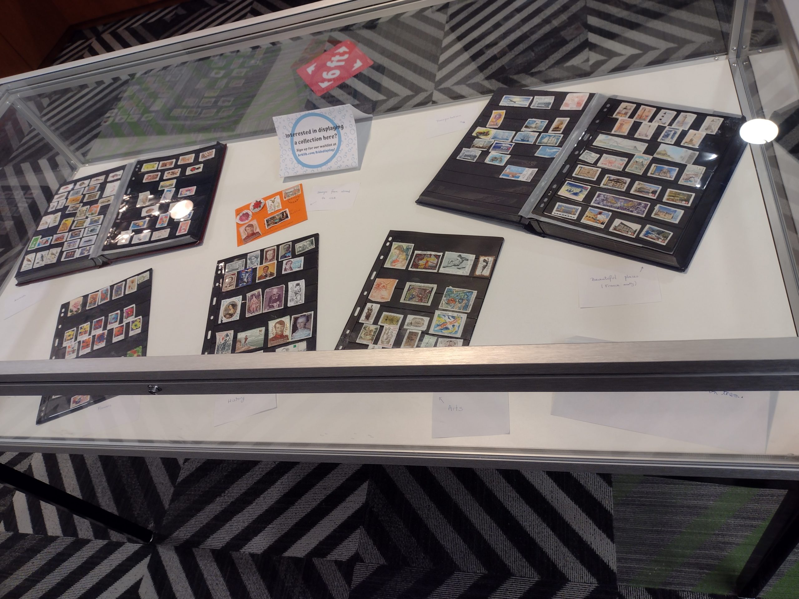 a stamp collection stored in stamp binders flipped open for viewing, displayed in our flat display case