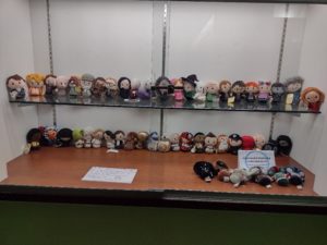 plush doll figurines from popular series like Star Wars and Harry Potter, displayed in a lit wall display case