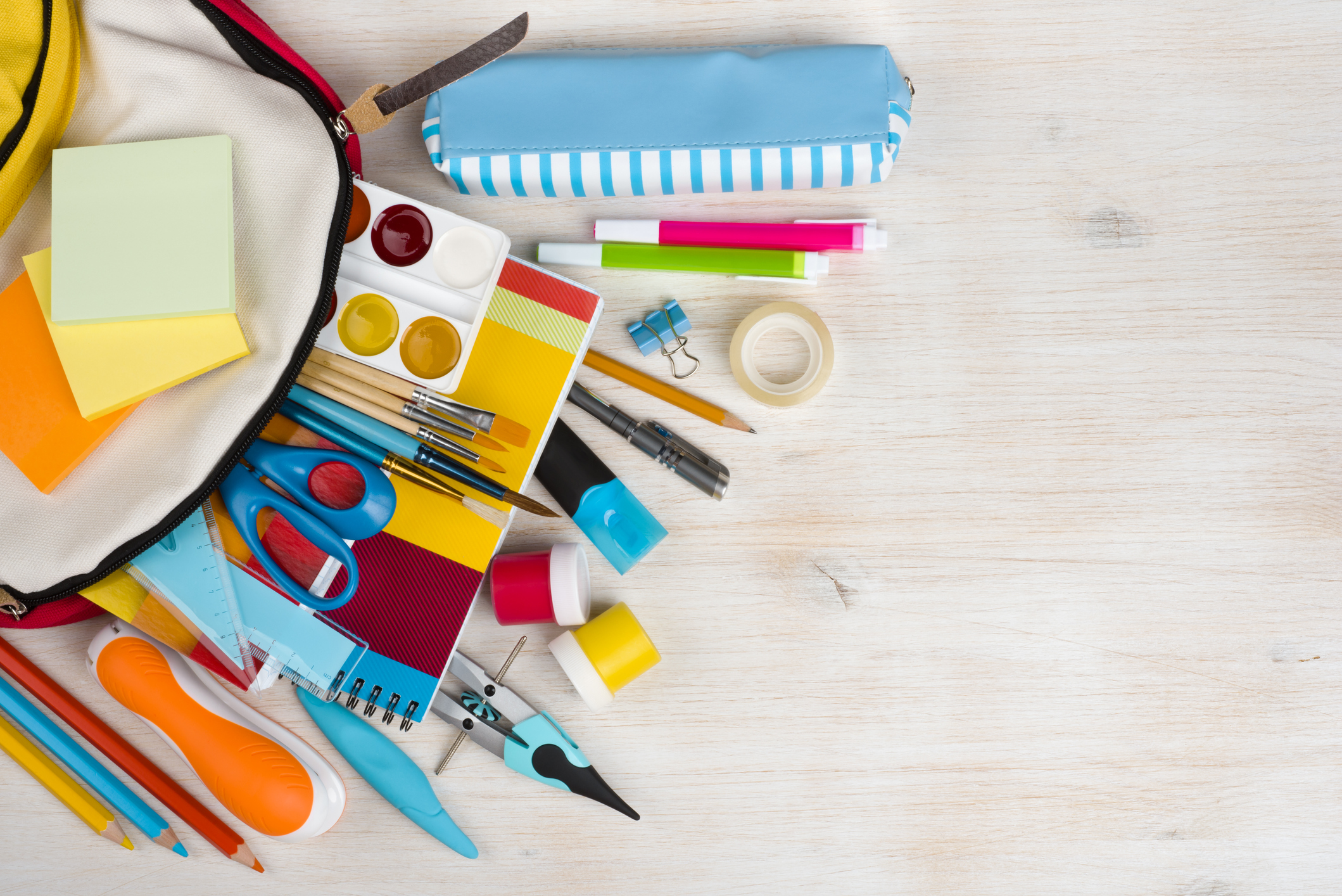 Various craft and stationary supplies splayed in an arc over a wooden texture background