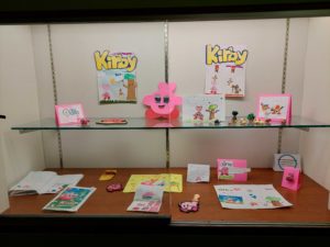 display case filled with Kirby art, figures, and drawings