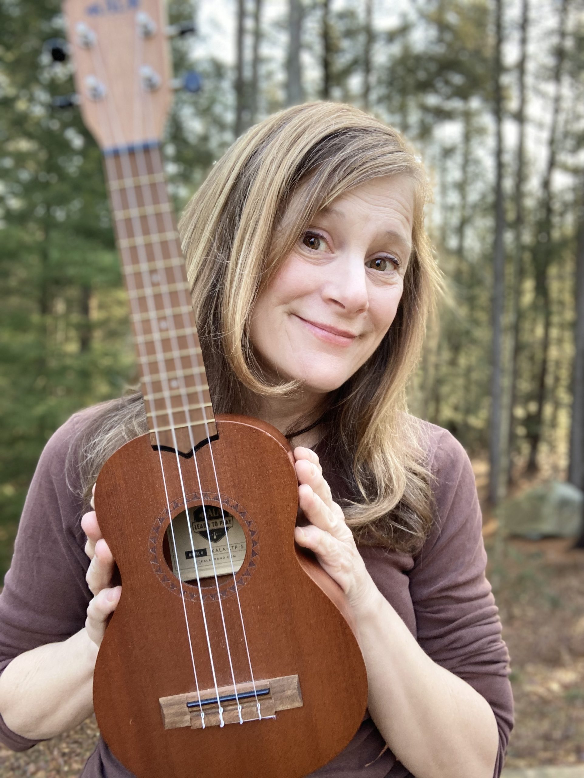 Julie Stepanek poses in woods with ukulele