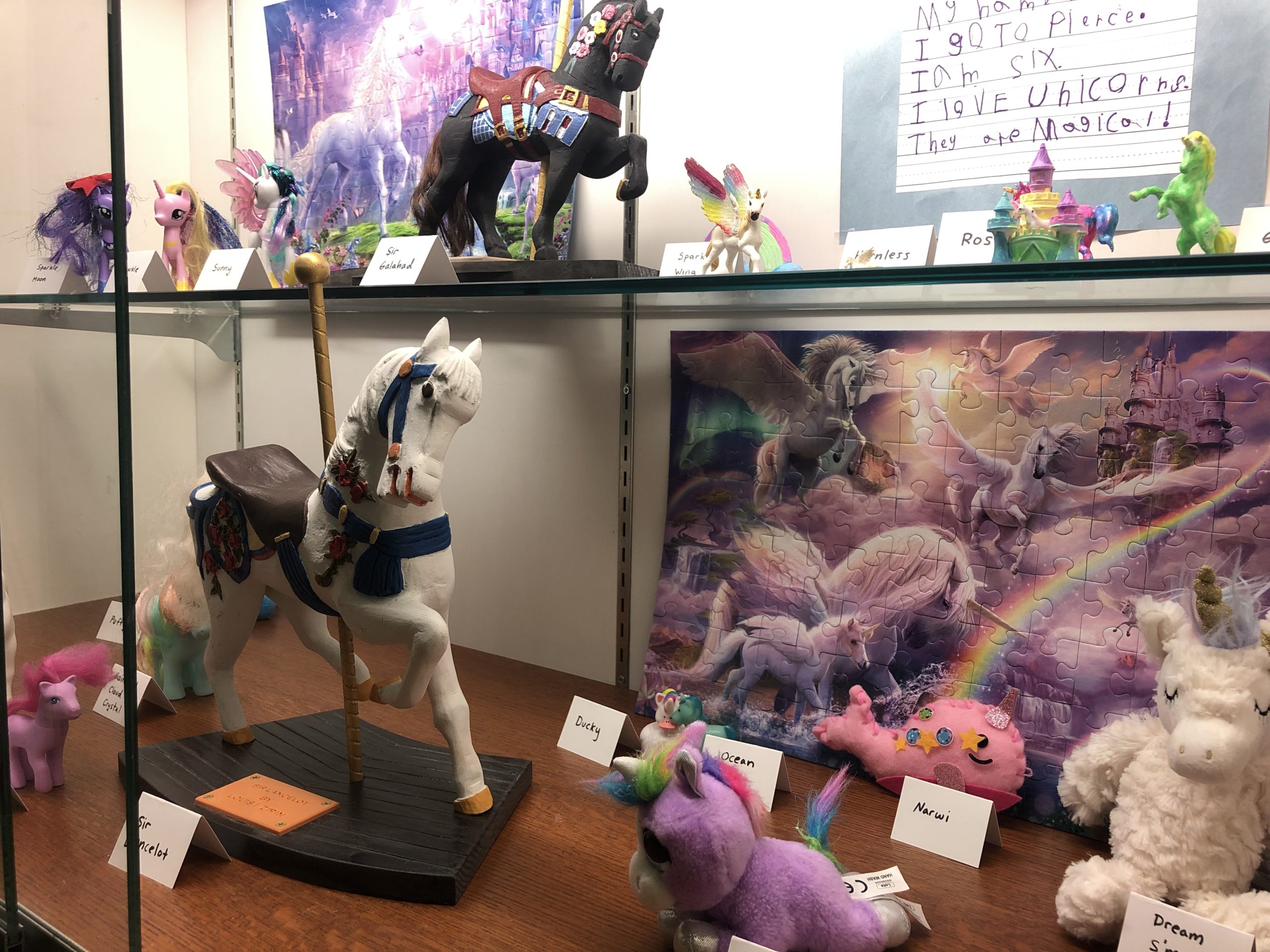 Display case featuring a collection of toy unicorns