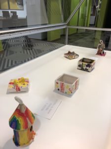 Assorted painted, ceramic birdhouses and boxes in a display case