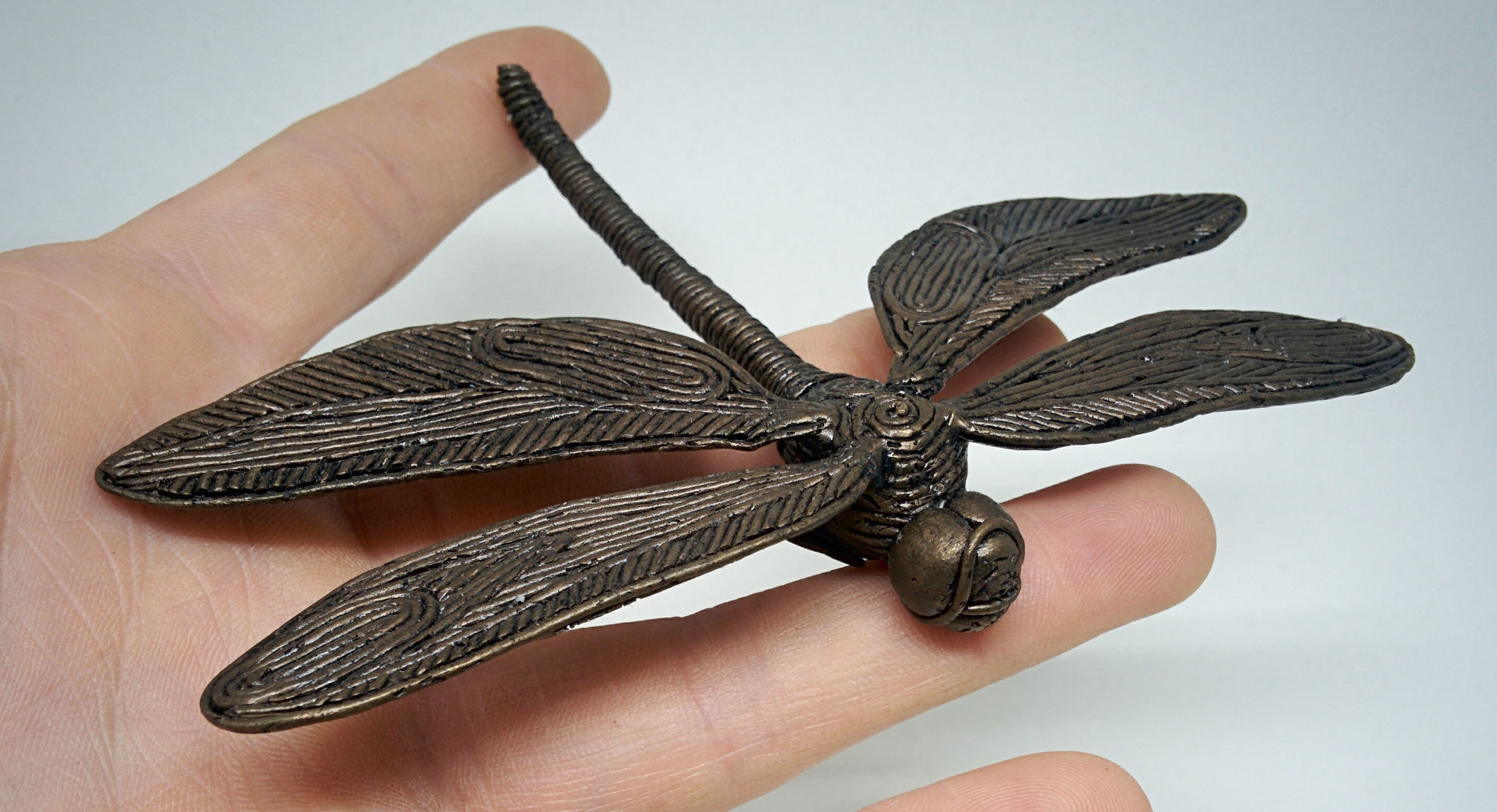 metal dragonfly sculpture held in open hand
