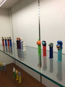 Pez dispenser collection in a display case, including Halloween-themed Pez, U.S. presidents, and Frozen characters