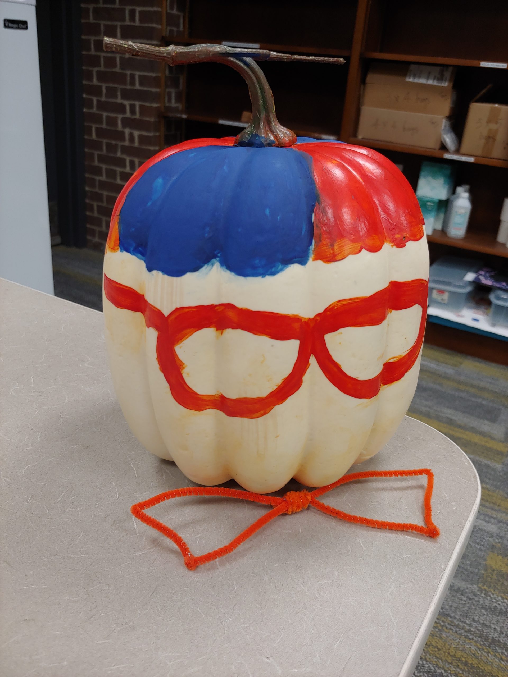 A pumpkin painted to look like Blippi with a pipe cleaner bowtie.