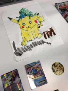 Drawing of Pikachu in a display case with Pokémon cards