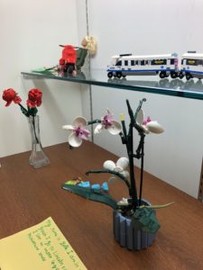 Display case of LEGO creations including flowers and a miniature train