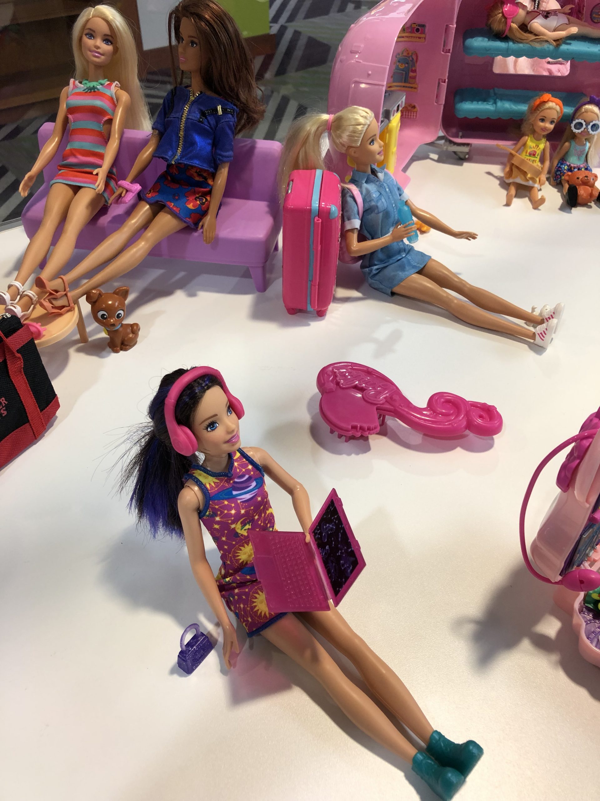 Barbie wearing headphones and holding a laptop in a display case of dolls