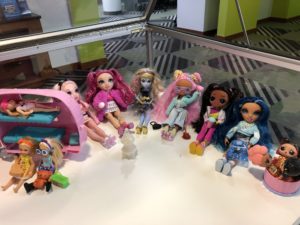 Collection of dolls of different races and hairstyles in a display case