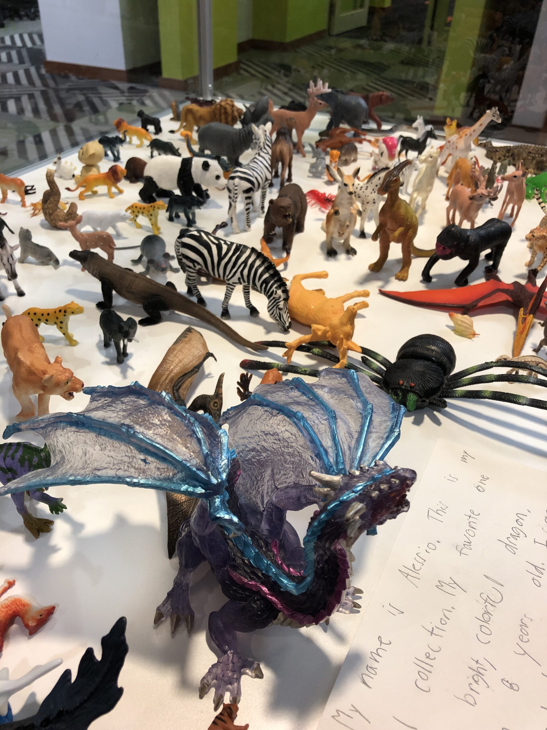 Collection of plastic toy animals including a dragon, panda, zebra, and more