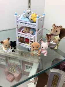 Baby Calico Critter toys in and around a toy crib.