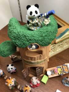 Panda Calico Critter toy using a telescope atop a toy treehouse.