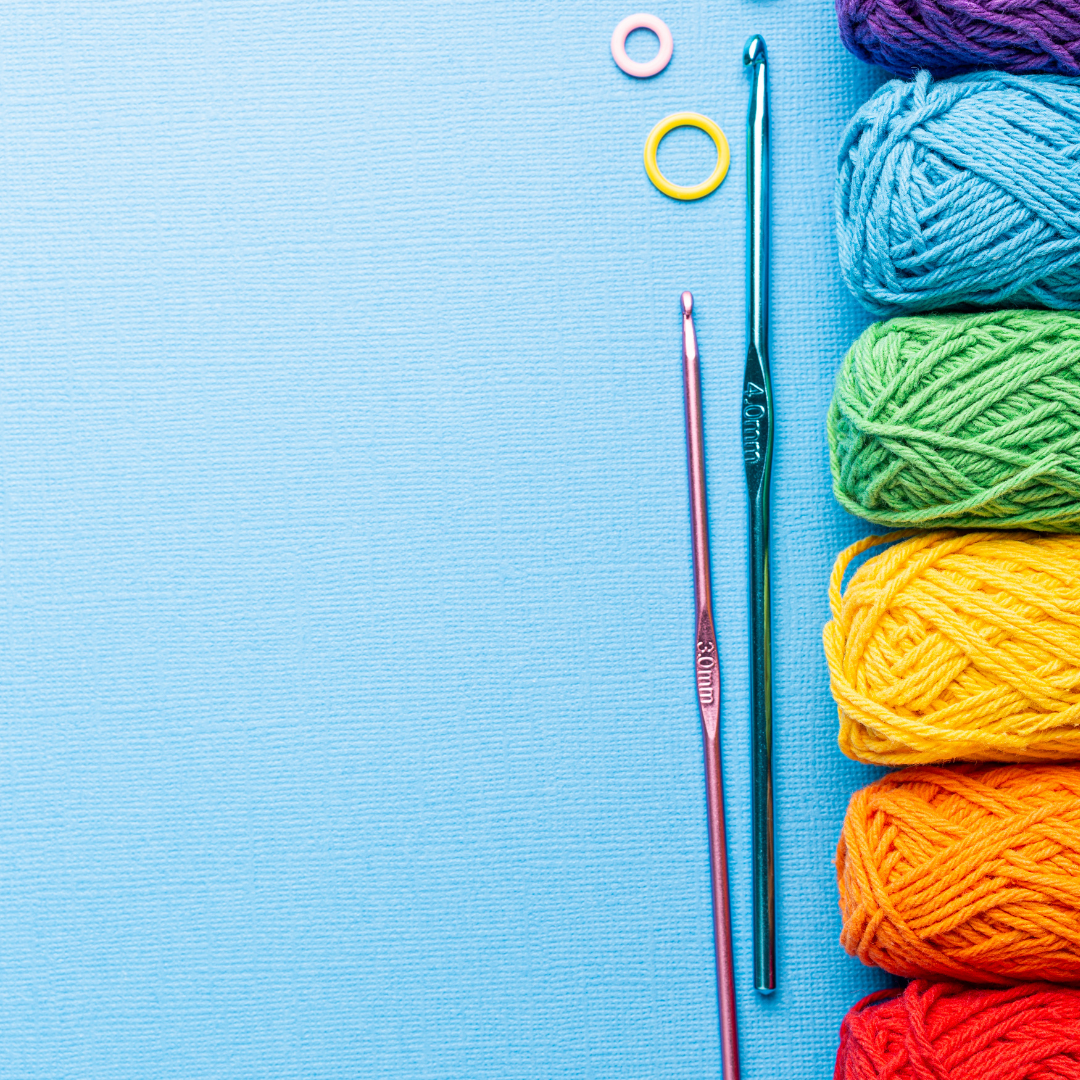 rainbow yarn and crochet hooks on a blue background