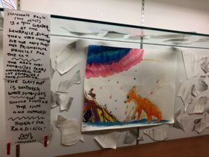Drawing of a cat, tree, squirrel, and colorful clouds, surrounded by shattered abstract shapes. Next to art is a hand-written artist statement.