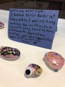 Painted rocks with gems and googly eyes, with a hand-written artist statement.