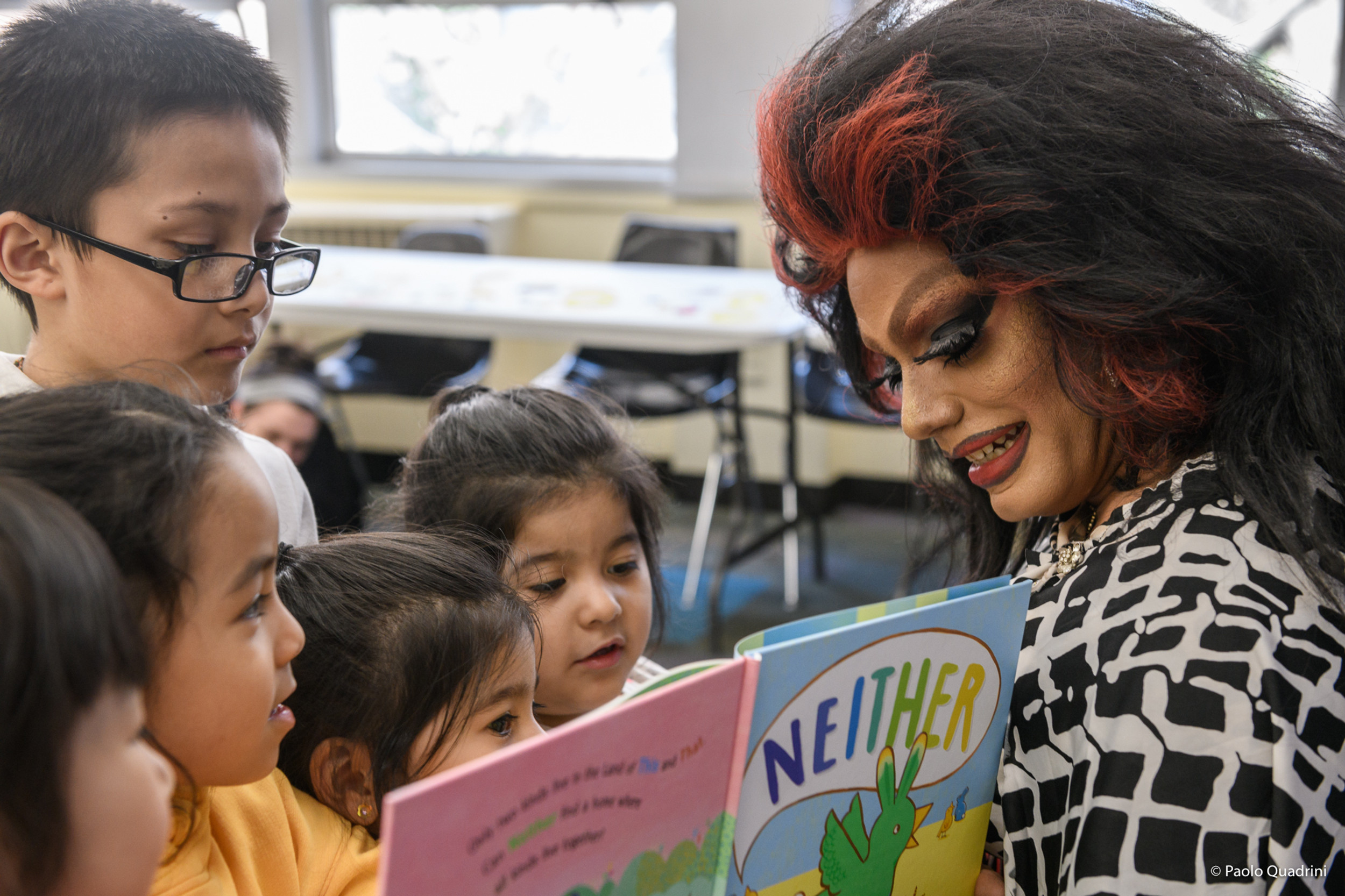 a drag queen reads the book "Neither" to a group of children in a classroom