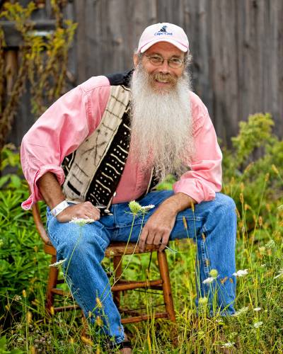 storyteller Davis Bates sits on a stool in a grassy backyard