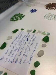 A display case of sea glass, arranged in piles by color