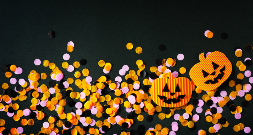 Black, orange, and pink confetti, and two paper jack-o-lanterns on a black background