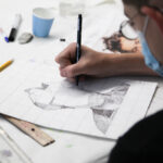 A photo looking over the shoulder of a person sketching.