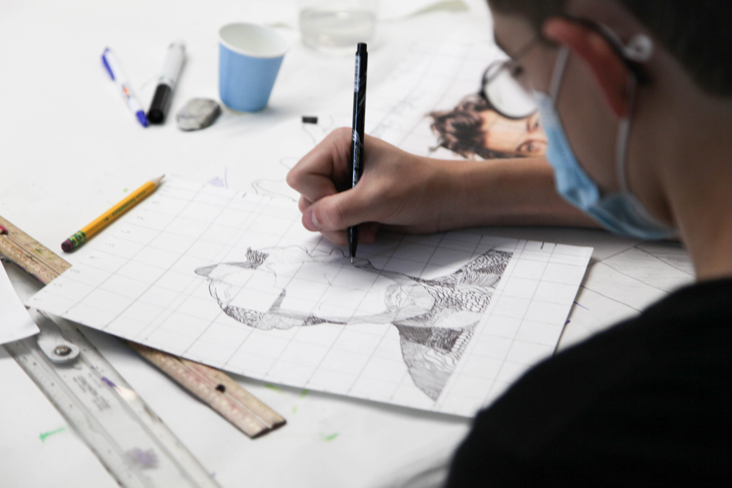 A photo looking over the shoulder of a person sketching.
