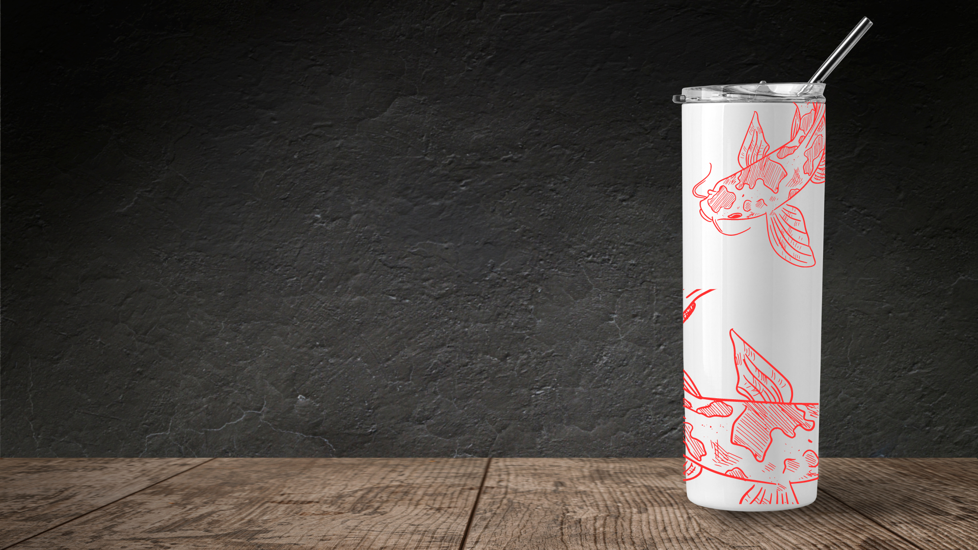 A tall white tumbler decorated with bright red sketches of catfish sits on a wooden tabletop against a dark gray background.
