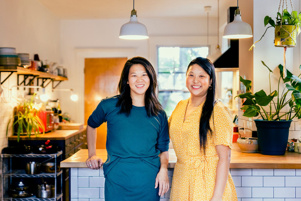 Mei and Irene Li stand in front of a kitchen counter, smiling at the camera