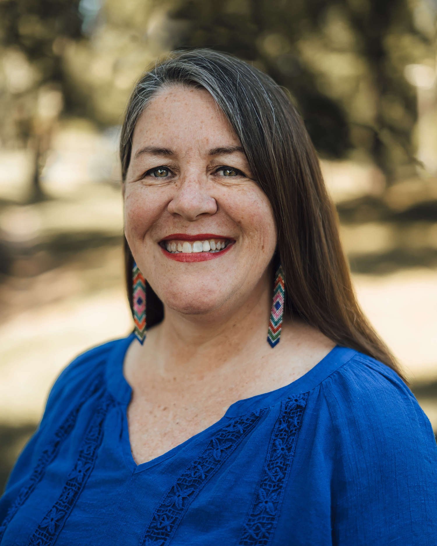 headshot of author traci sorell, an Indigenous woman, wearing a blue shirt and beaded earrings.