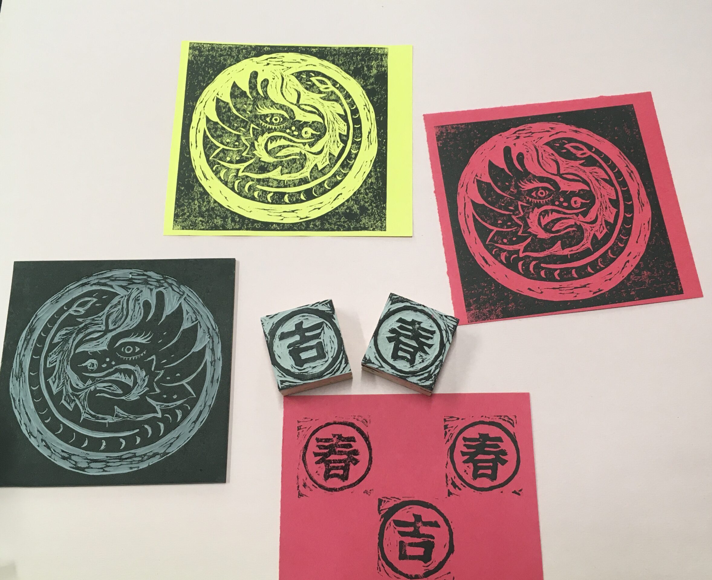 sheets of red and yellow paper with block printed dragon designs on them