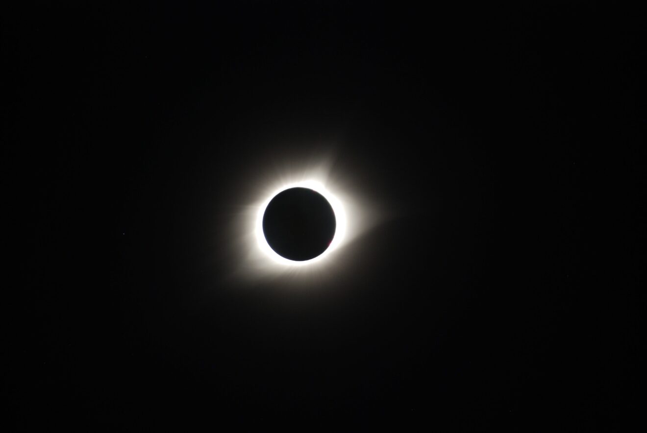 Image of a solar eclipse, a black background with a black circle that is illuminated from behind.