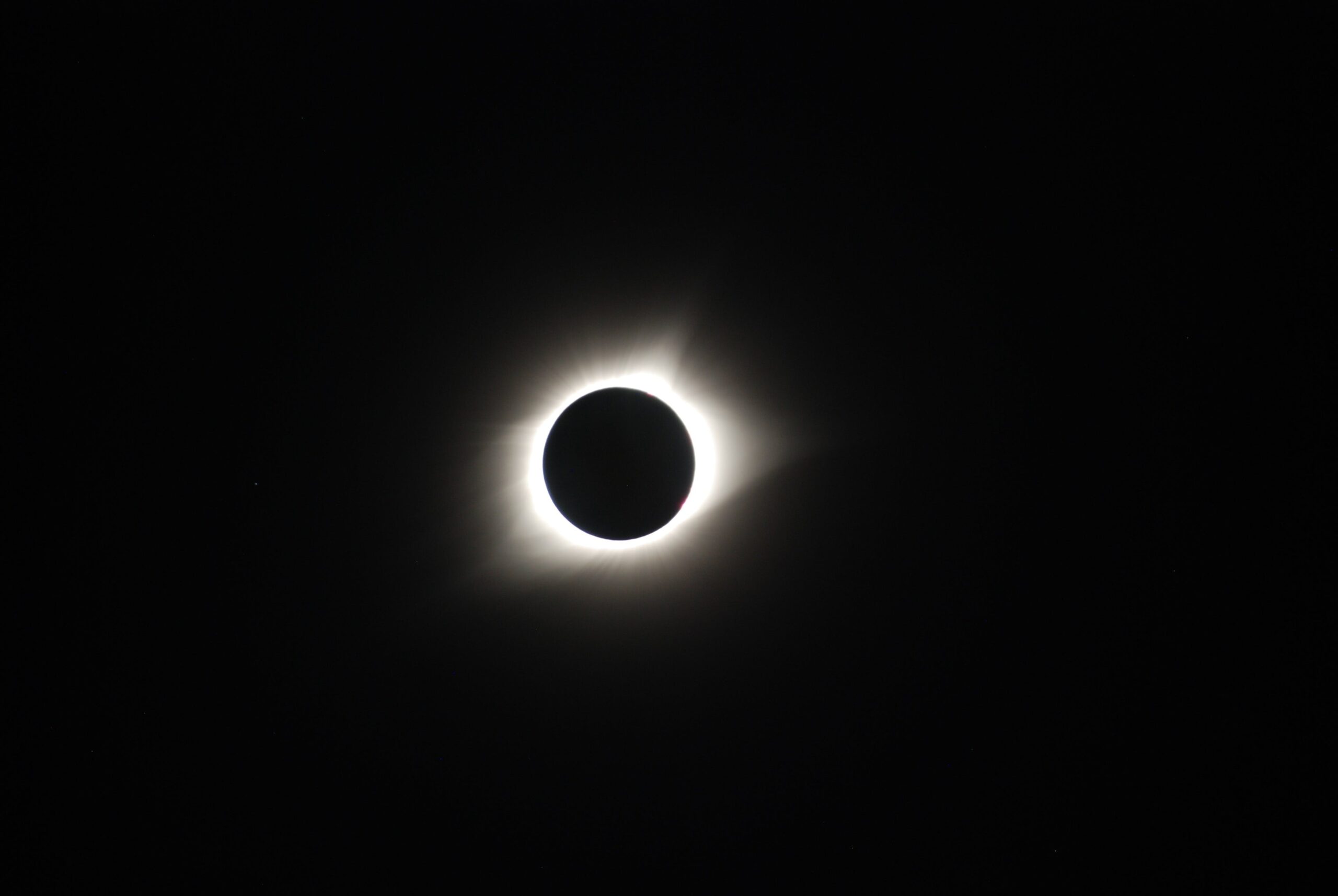 Image of a solar eclipse, a black background with a black circle that is illuminated from behind.