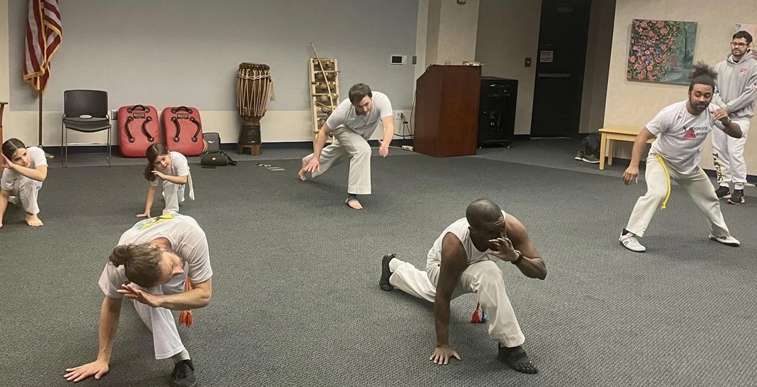 A group of adults and children doing capoeira together.