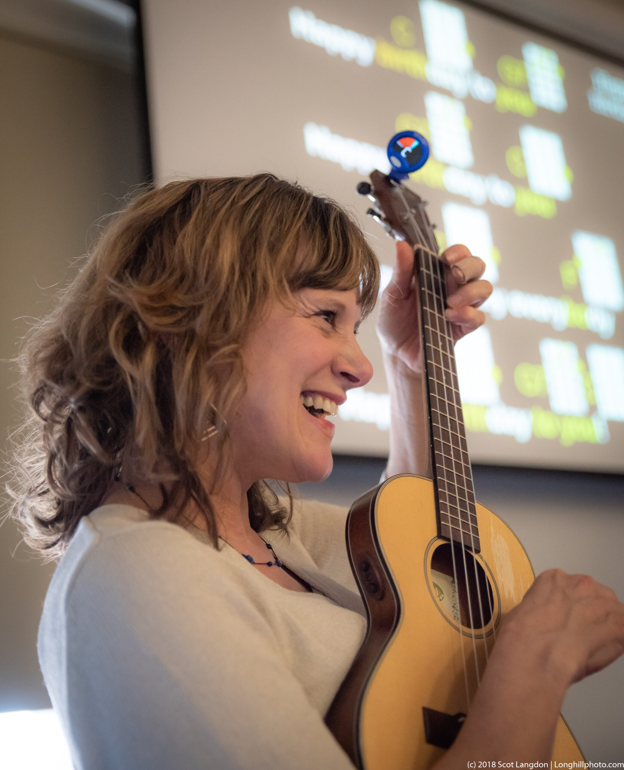 A smiling Julie Stepanek plays the ukulele.